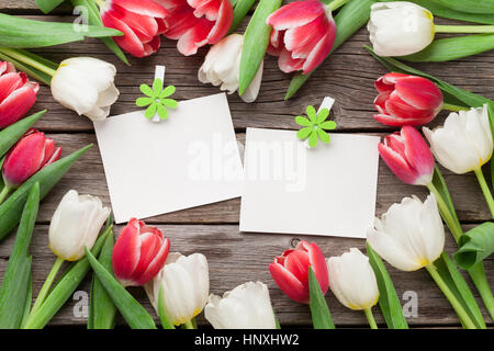 Colorful tulips and two photo frames on wooden background. Red and white. Top view Stock Photo