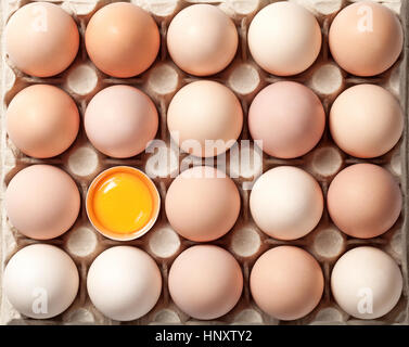 Chicken eggs on cardboard tray for background. One egg broken. Top view Stock Photo