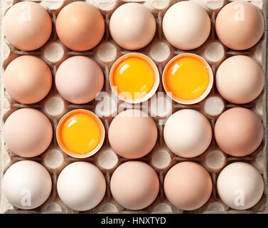 Chicken eggs on cardboard tray for background. Three eggs broken. Top view Stock Photo