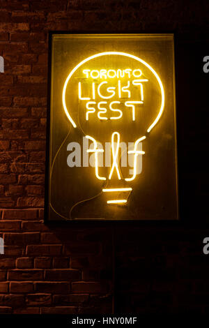 Neon sign logo for the Toronto Light Festival on a brick wall at night in the Distillery District Stock Photo