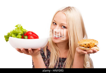 woman choosing what to eat, vegetables or burger, isolated against white background Stock Photo