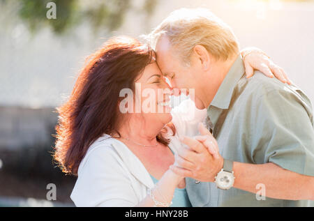 Happy Middle Aged Couple Enjoy A Romantic Slow Dance Outside. Stock Photo