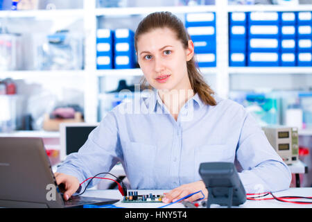 Engineer working with circuits. A woman engineer solders circuits sitting at a table.  Microchip production factory. Technological process. Assembling Stock Photo