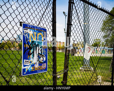 Heavy graffiti on sign mounted on chain link fence in Stock Photo