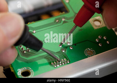 Technician testing contact points on circuit board with a voltmeter - USA Stock Photo