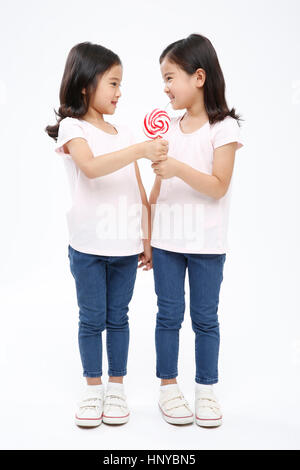 Smiling twin girls with lollipop Stock Photo