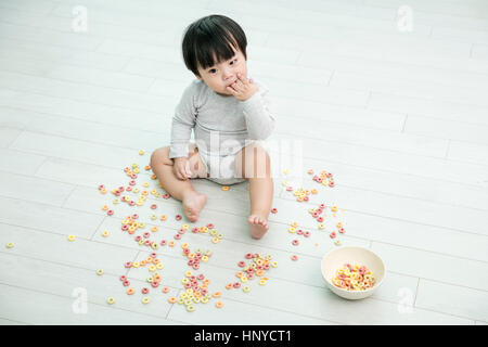 Baby boy making mess with cereal Stock Photo