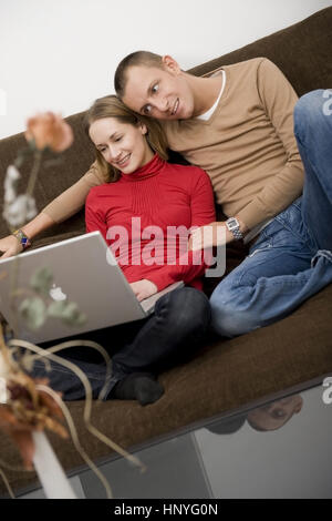 Model release , Junges Paar sitzt mit Laptop auf der Couch - couple using laptop on couch Stock Photo