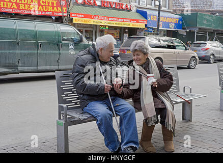A visually impaired couple seated on a bench in the winter in Jackson Heights Queens New York City Stock Photo