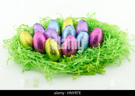 Multi coloured foil covered chocolate Easter Eggs on green paper Stock Photo