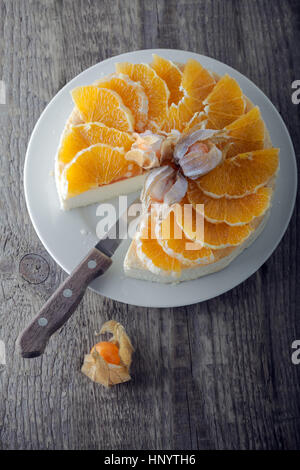 Cheesecake decorated with oranges and physalis. Stock Photo