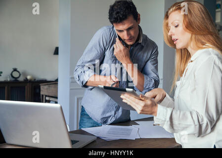 Couple doing business with cell phone and digital tablet at home Stock Photo