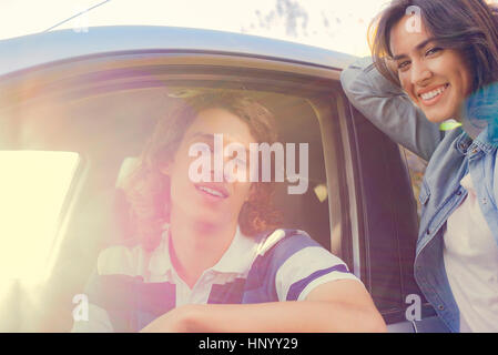 Woman standing next to man sitting in car Stock Photo
