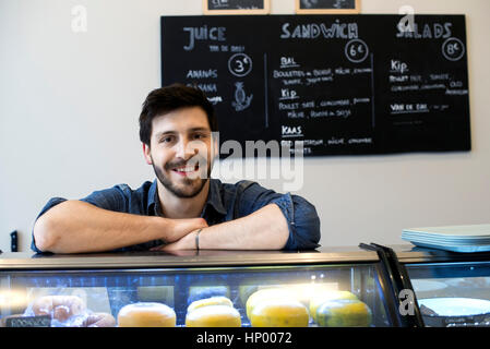 Cafe owner standing behind refrigerator case Stock Photo