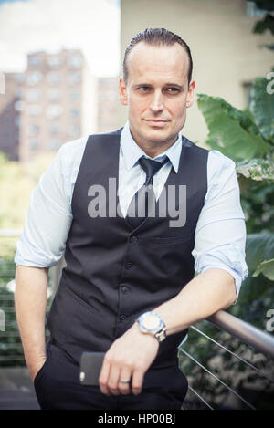 Businessman leaning against balcony railing, portrait Stock Photo
