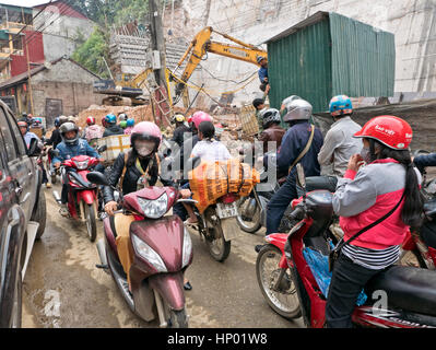 People riding scooters & motorcycles, wearing helmets & protective gear, city street, parked automobile, congested vehicle traffic. Stock Photo