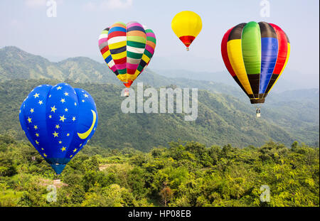 summer landscape with colorful hot air balloon flying above Alps mountains lake and green field or meadow and forest in Thailand Stock Photo