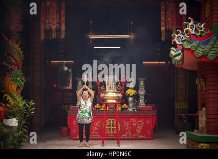 Kuala Lumpur, MALAYSIA - NOVEMBER 9: woman burning incense sticks for ancestors in chinese temple on November 9, 2014 at Kuala Lumpur, Malaysia Stock Photo