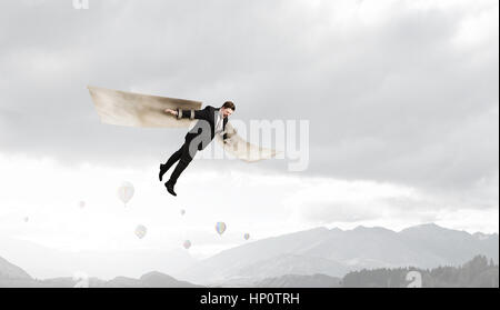 Young businessman with paper wings flying in sky Stock Photo