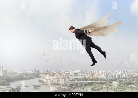 Young businessman with paper wings flying in sky Stock Photo