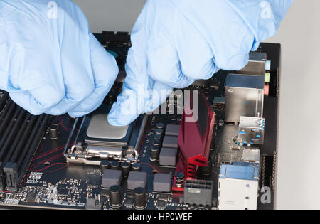 Close up of man hands with gloves openning slot for CPU on  motherboard. Stock Photo