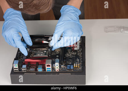 Young man with gloves installing part of CPU cooler fan. Stock Photo