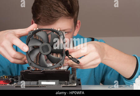 Young man installing CPU cooler fan on new, modern gaming motherboard. Stock Photo