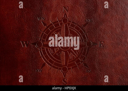 Compass print on brown leather cover closeup. East west south north sides Stock Photo