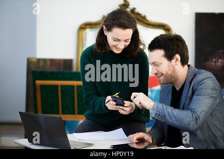 Woman sharing content of smartphone with colleague Stock Photo