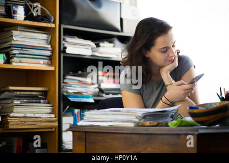 Office worker taking break to browse social media using smartphone Stock Photo