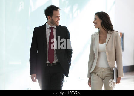Colleagues chatting while walking together in office Stock Photo