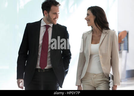 Colleagues chatting while walking together in office Stock Photo
