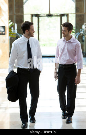 Business colleagues chatting while walking together Stock Photo