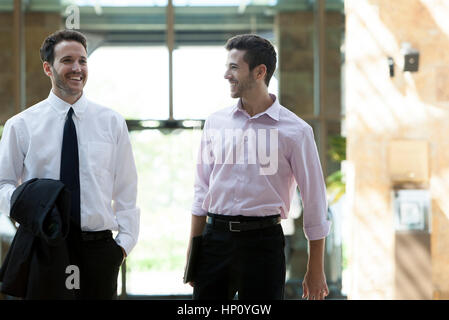 Business colleagues chatting while walking together Stock Photo