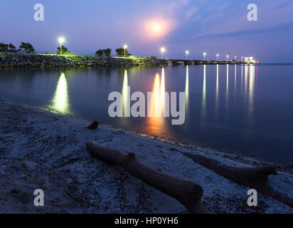 A panoramic shot of the Suncor Pier (Petro Canada Pier) at night with a full moon in Oakville, Ontario, Canada. Stock Photo