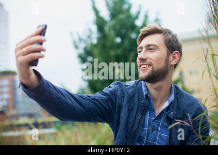 Young man using smartphone to take a selfie outdoors Stock Photo