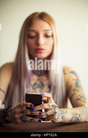 Tattooed woman using smartphone Stock Photo