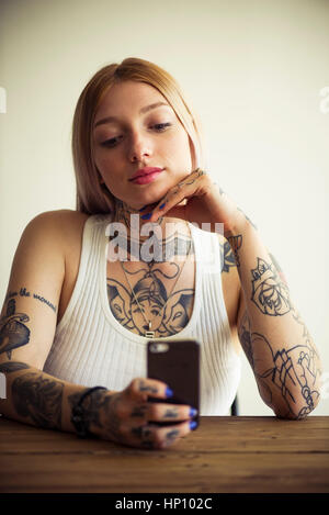 Tattooed woman using smartphone Stock Photo