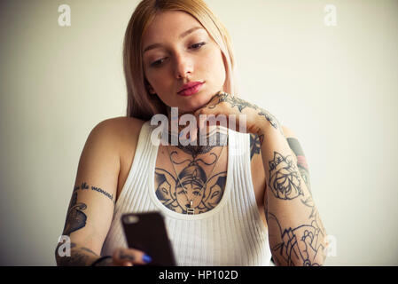 Tattooed woman using smartphone Stock Photo