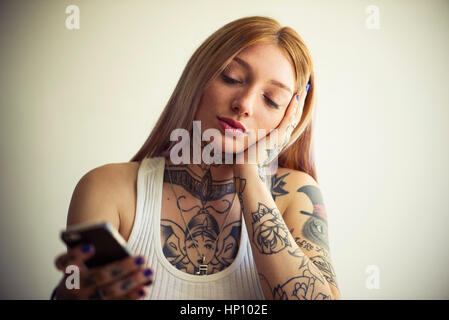 Tattooed woman using smartphone Stock Photo