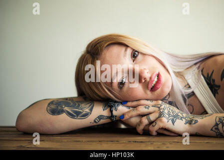 Tattooed woman resting head on arms, portrait Stock Photo