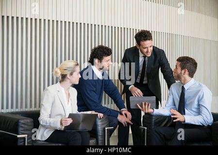 Business team members collaborate on project using digital tablet Stock Photo