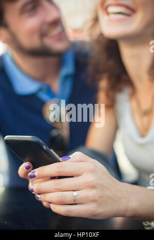 Woman using smartphone, laughing with boyfriend Stock Photo