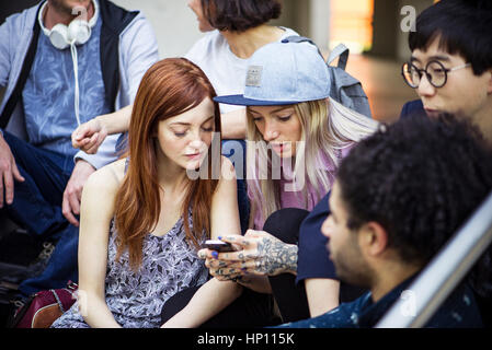 Young adult friends hanging out and using smartphone together Stock Photo