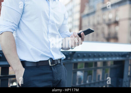 Businessman holding smartphone, mid section Stock Photo