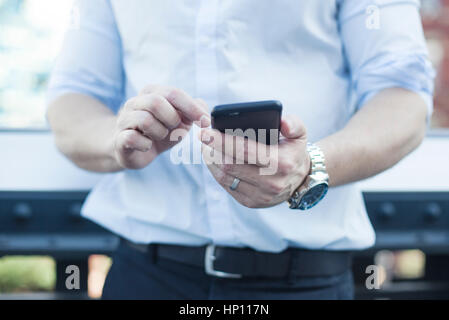 Man using smartphone, mid section Stock Photo