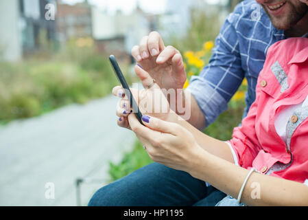Couple using smartphone together outdoors Stock Photo