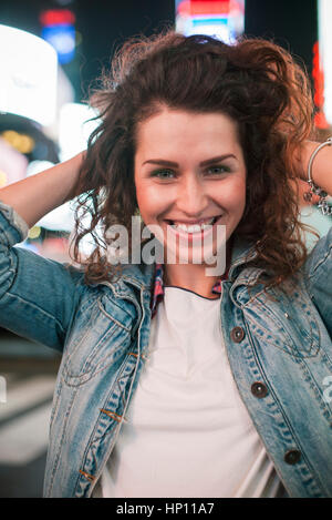Young woman standing in illuminated city street Stock Photo