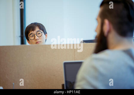 Coworkers chatting over cubicle wall Stock Photo