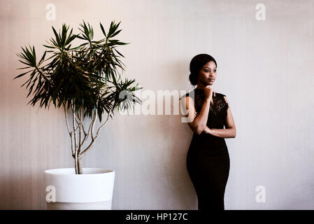 woman looking into distance thoughtfully while standing next to tree Stock Photo